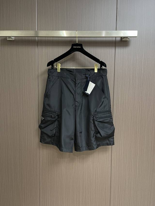 Prada普拉达男士三角形金属徽标饰尼龙装饰短裤，Prada将两种矛盾对立的风格融合，营造非同以往的新颖格调，衍生出经久不息的设计理念。此处，混搭理念阐释为前所